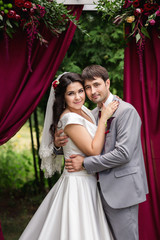 Portrait bride and groom near wedding arch