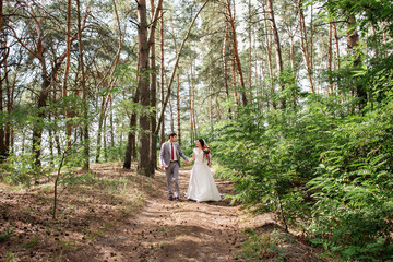 Bride and groom walking in forest in wedding day