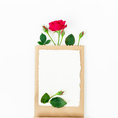 Red roses, branches, leaves, paper card and craft pack isolated on white background. Flat lay, top view