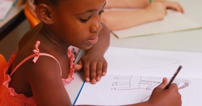 Schoolgirl doing her homework in classroom at school