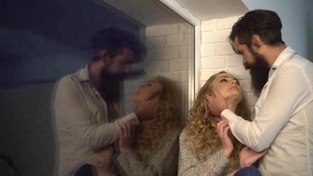 Curly blonde on a windowsill with her bearded boyfriend on a date. Young tender couple, romantic date near the window