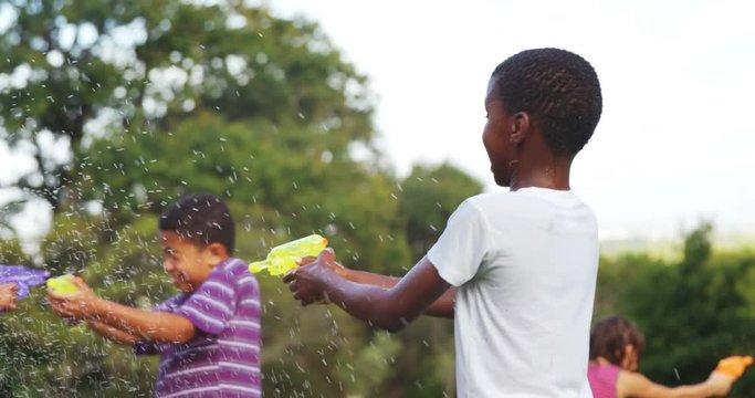 Group of kids playing with water gun in garden on a sunny day 4k