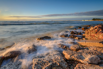 Fototapeta na wymiar Blurred waves on the rocky beach. Baltic Sea at sunset light. Poland.