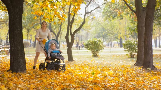4k footage of young mother running with baby pram at autumn park
