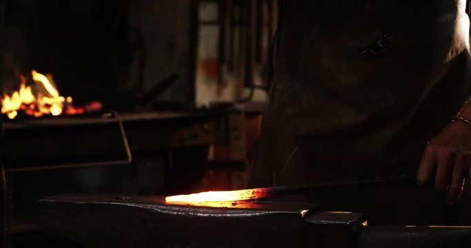 Mid-section of blacksmith working on a iron rod in workshop 4k