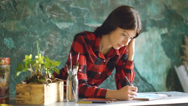 Portrait young woman artist painting scetch on paper notebook with pencil
