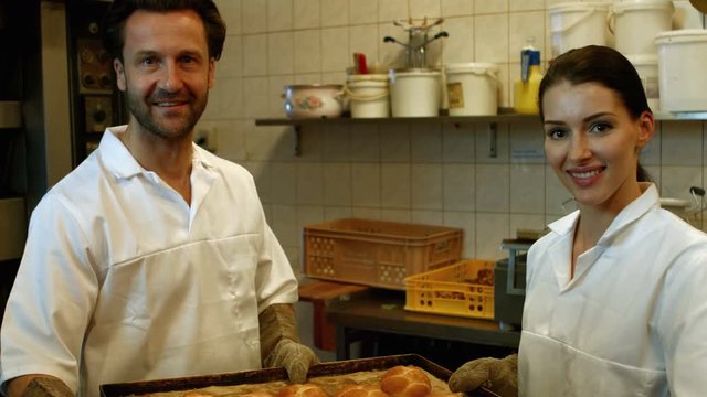 Bakers holding baked michetta in tray at bakery kitchen 4k