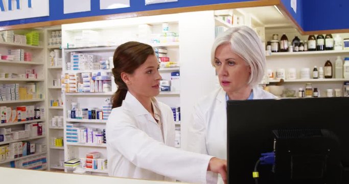 Pharmacists maintaining a record of medicine on computer in pharmacy