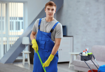 Young man with mop cleaning floor at home