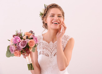 Young beautiful bride holding wedding bouquet on white background