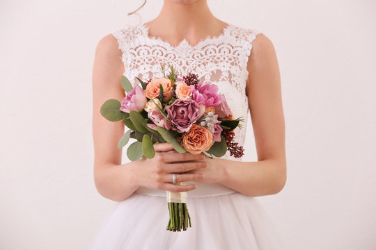 Bride holding wedding bouquet on white background, closeup
