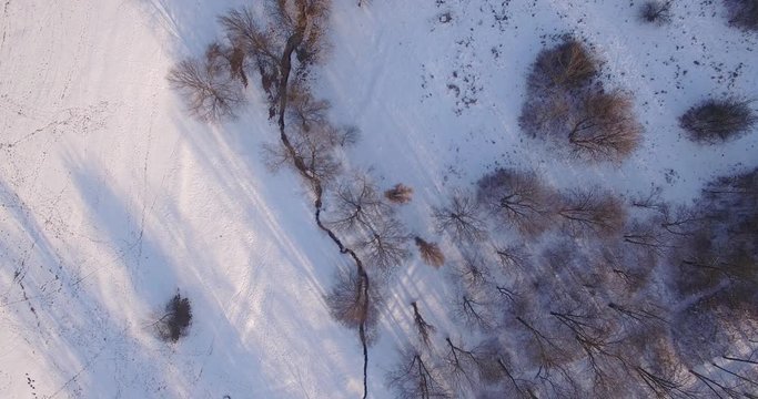Aerial view on a small stream in winter.Aerial footage over a little meandering stream in a snowy forest. Looking down 