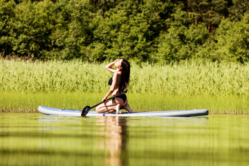 Fototapeta na wymiar Young attractive woman on stand up paddle board