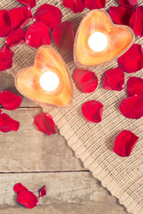 Two enlightened candles in heart-shaped candleholders with rose
