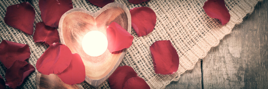 Two enlightened candles in heart-shaped candleholders with rose