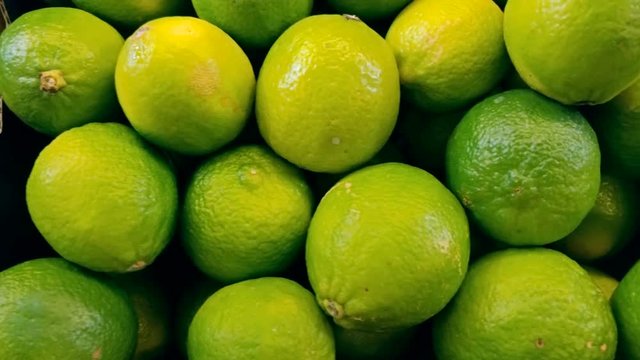 Closeup dolly shot of fresh ripe limes lying on counter at mall