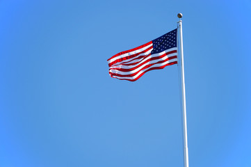 waving USA flag on pole against blue sky