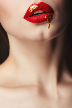 Sensual portrait of a girl with red lips and liquid paint on her face. Makeup simple and catchy. Close-up of mouth. Girl vamp.