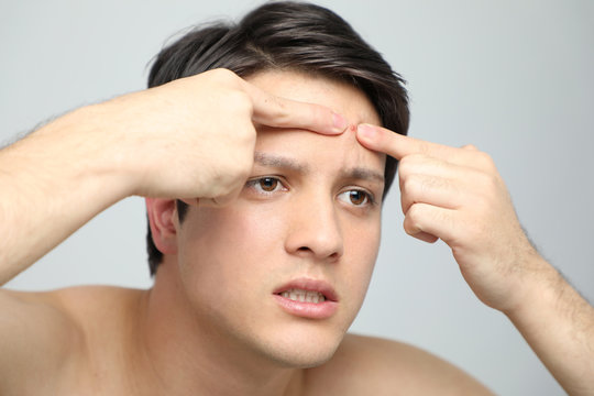 young man squeezing a pimple, men's skincare concept