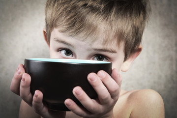 Hunger.   Boy holding an empty bowl.