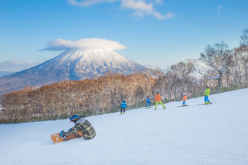 People skiing on the snow slope and Mt.Yotei as a background in Niseko Ski area, Hokkaido, Japan - obrazy, fototapety, plakaty