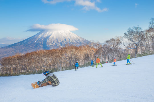 People skiing on the snow slope and Mt.Yotei as a background in Niseko Ski area, Hokkaido, Japan