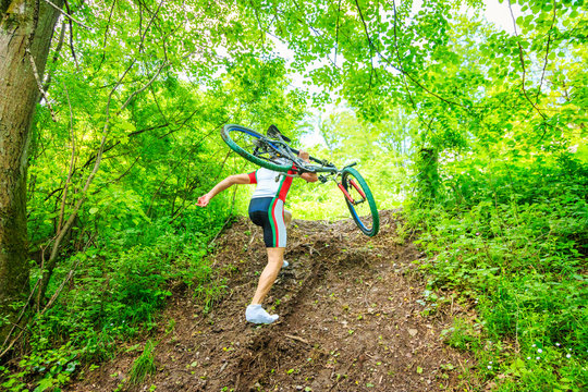 Young Man Carrying His Mountain Bike Uphill