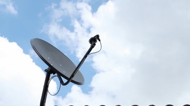 black antenna communication satellite dish over sky, time-lapse