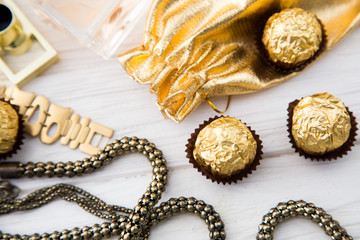 Women's set of accessories and sweets in golden color on wooden