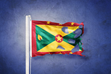 Torn flag of Grenada flying against grunge background