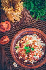 Penne pasta in tomato sauce with chicken, tomatoes decorated with parsley.
