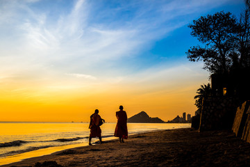 Fototapeta na wymiar Buddhist monks walk collecting alms, morning beach.