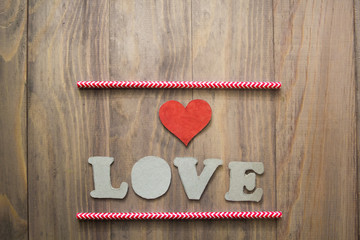 background with cocktail straws and a heart and the words love on wooden background