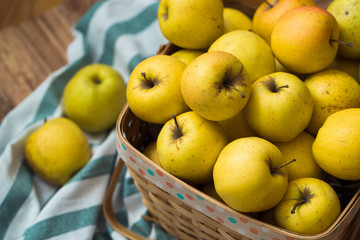 Fototapeta na wymiar Golden apples in a basket on a wooden background