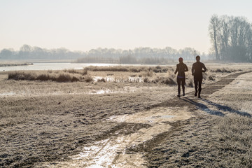 Man and woman in sportswear running in a winter landscape