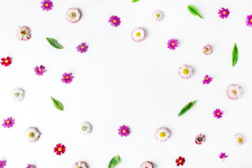 Frame made of chamomile buds, leaves, petals on white background. Flat lay, top view