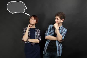 A couple in love posing on a black background. The guy looks at the girl dreaming.