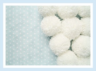 white pompoms on a pale blue polka dot background