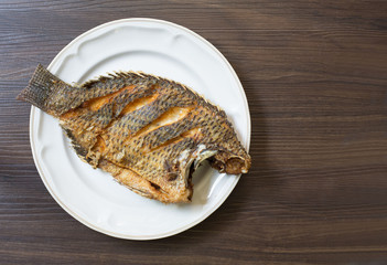  Fried fish in white dish on dark brown wooden plate thai food