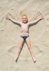 Fototapeta premium Boy making an angel on a sand