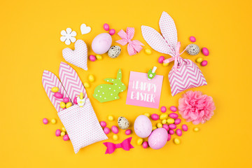 Easter decoration with eggs, bunny bag and candy on yellow background