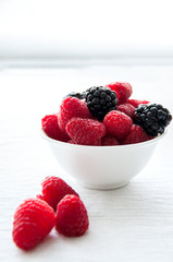Fresh raw berries in a white bowl on a table