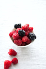 Fresh raw berries in a white bowl on a table