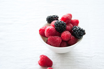 Fresh raw berries in a white bowl on a table