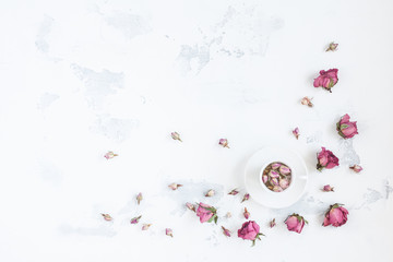 Composition with cup of tea and dried rose flowers. Flat lay, top view
