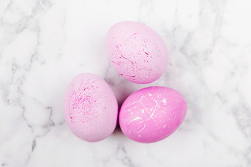 Minimal trendy pink easter eggs on marble background from above.