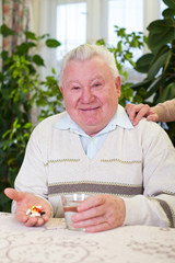 Elderly man holding pills and water