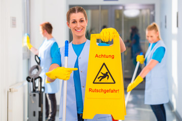 Putzfrau zeigt Warnschild 