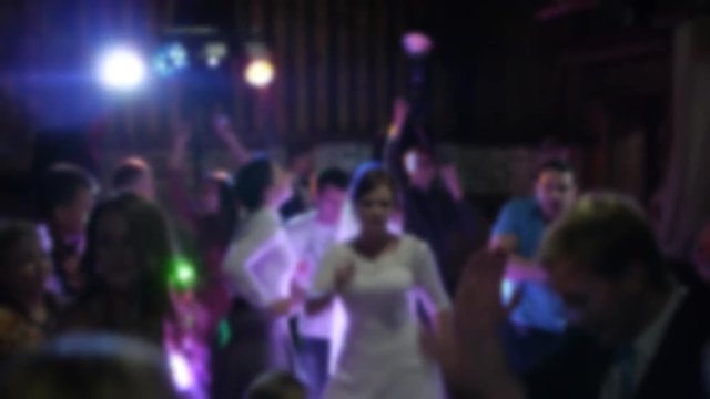 the couple with friends celebrating a wedding. dancing in a club under bright light. camera blur