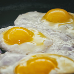 Vintage photo of Fried eggs in a frying pan. Process of cooking eggs closeup. Food Background